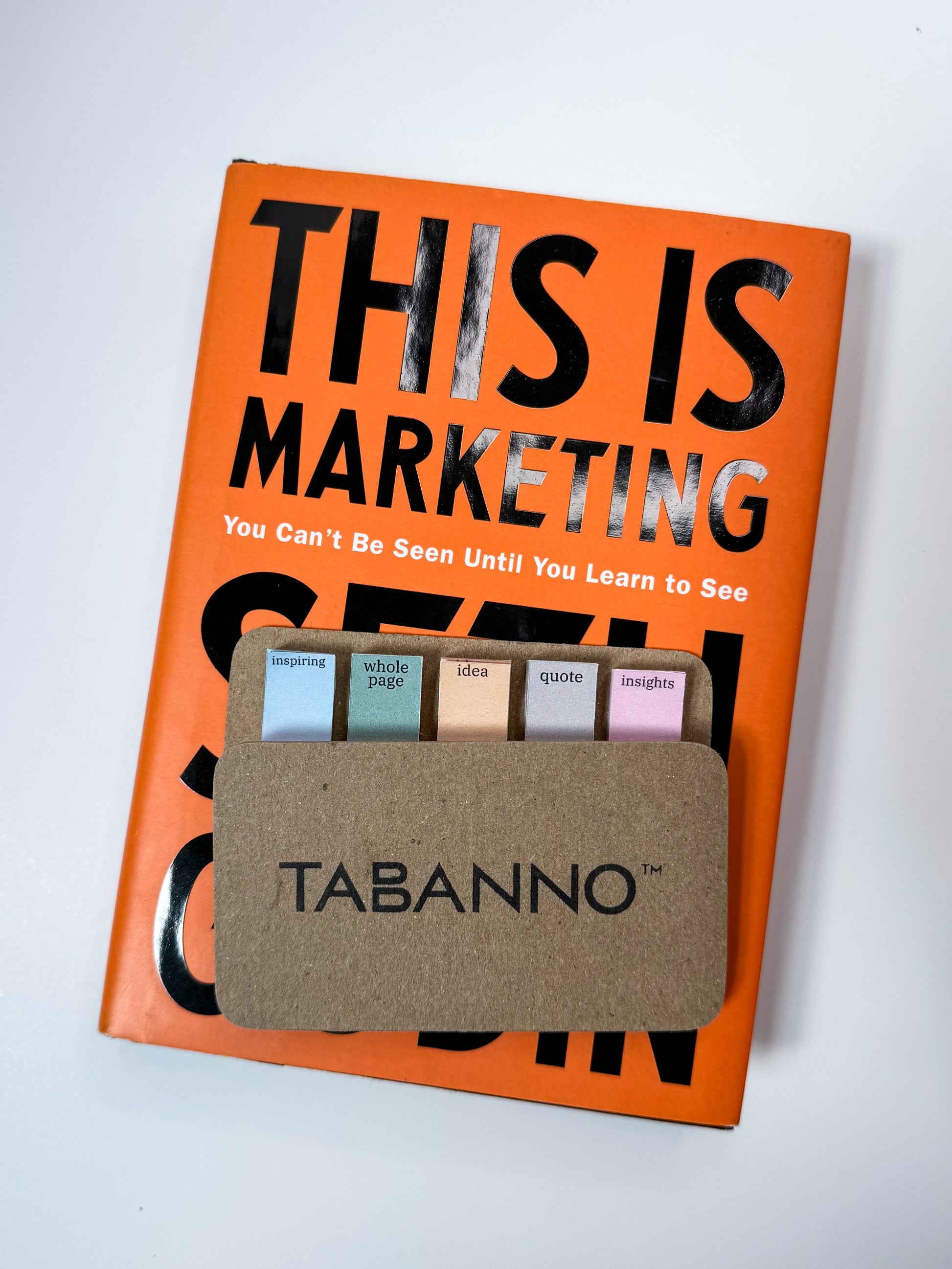 Book titled 'This is Marketing' with Tabanno™ color tabs on a white background