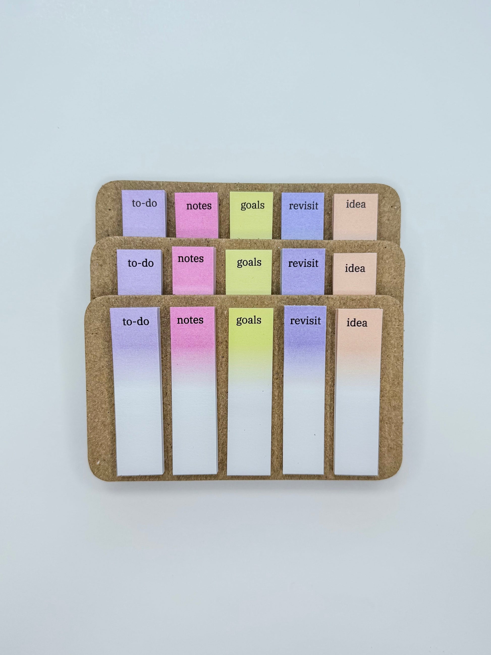 Three sets of planner inserts with pastel gradient tabs labeled to-do, notes, goals, revisit, and ideas, arranged on a light gray background.